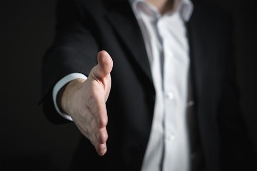 Home Close-up of a businessman extending hand for a handshake, symbolizing agreement and partnership.
